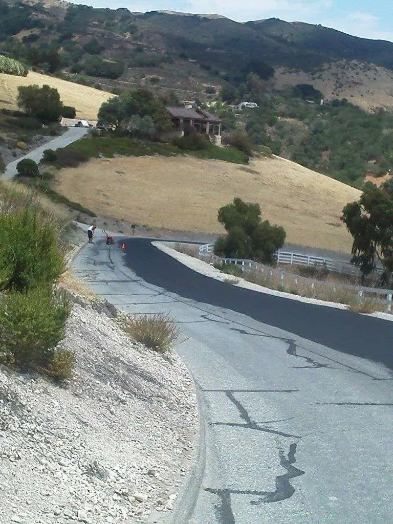 A freshly paved private road winding through the Central Valley foothills.