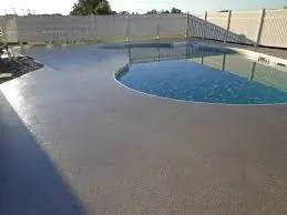 A textured concrete pool deck around a residential swimming pool.