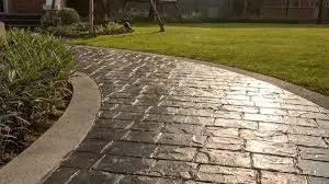 A curving stamped concrete walkway in cobblestone pattern.