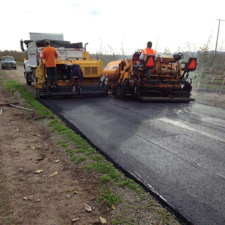 Paver and roller laying hot mix.